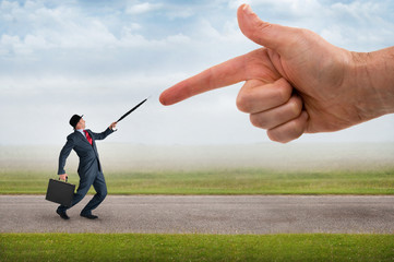 giant finger pointing aggressively at a defensive businessman