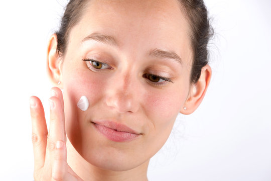Young attractive woman applying cream on her skin