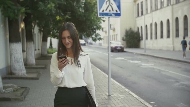 Woman uses smartphone walking in old city. slow mo