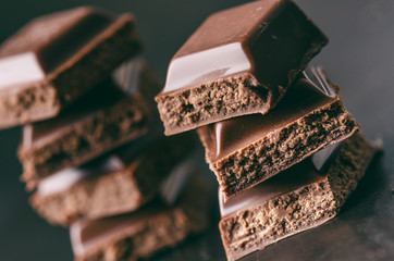 Two chocolate buildings on a dark background. energy and sugar. Broken bar. Chocolate blocks stack 