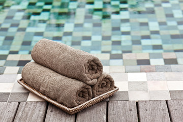 Brown towels in wicker basket at a luxury swimming pool