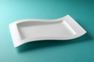 white square plate with a special design on a sea-green table