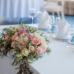 Table set for an event party or wedding reception. Large floral arrangement of roses and peonies