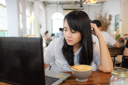 Asian hipster businesswoman working on laptop with cup of coffee