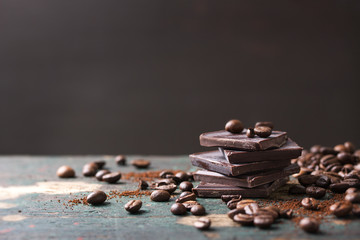 Stack of chocolate chunks with coffee beans on a wooden background, horizontal with copy space