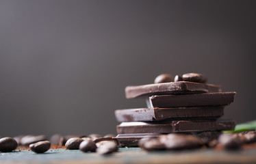 Stack of chocolate chunks with coffee beans on a wooden background, horizontal with copy space