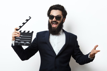 Young man in a suit holding movie clapperboard - obrazy, fototapety, plakaty