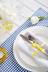 Table setting with blue checkered tablecloth, white napkin 