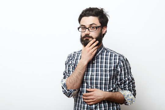 man in glasses touching his beard and thinking