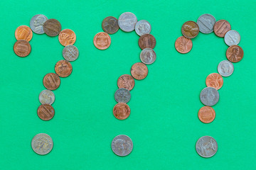 Coins forming three question marks on green background