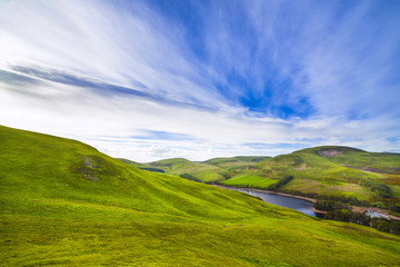 Landscape scenery of green valley, hill, river and cloudy blue sky