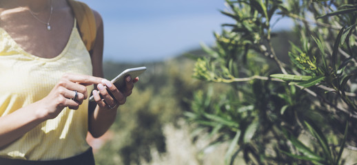 Hipster young girl with bright backpack looking at phone and map. Said view tourist traveler on background mountain, blue sea. Mock up for text message. Female hands using smartphone, holding gadget