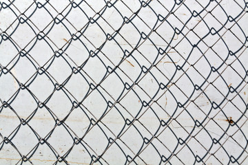 abstract chain link fence texture against grungy color wall.
