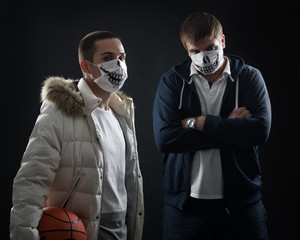 studio on a black background portrait of two men in masks with basketball