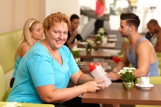 Overweight woman having refreshment in gym