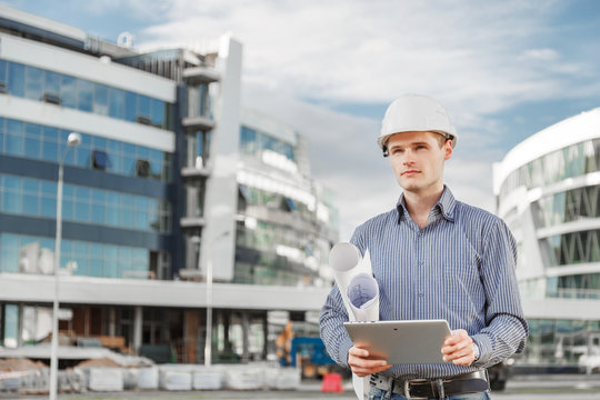 Portrait of young architect or chief engineer uses digital tablet at the construction site