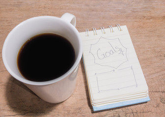 White Cup of coffee and litter notebook with word 