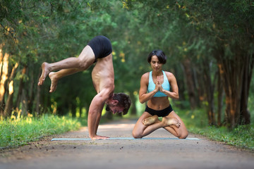 Fototapeta premium Acro yoga, two person practice yoga in pair, couple doing stretching exercise in the garden