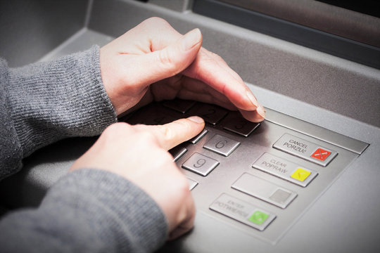 Woman's hand covers his hand when entering your PIN into an ATM
