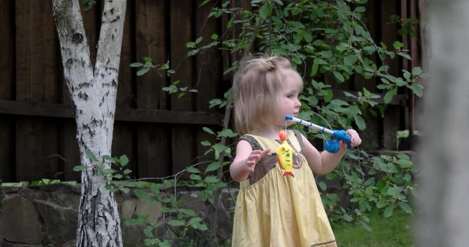 a Cute Baby Girl Plays With Her Toy Fishing Set Outdoor
