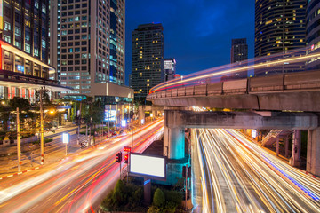Traffic light and sky train in busy light trails at night - Bangkok, Thailand