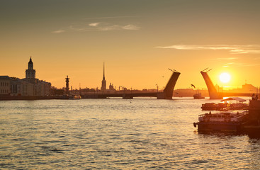 Russia, Saint-Petersburg, 03 July 2016: Closing of Palace Bridge at sunrise, the Peter and Paul Fortress Spike in the orange sky, Rostral colomn, ships, boats, the traffic beginning, sun, 