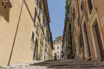 Gasse in Rom mit Treppe und einem Trinkbrunnen in der Bildmitte aus einer Untersicht