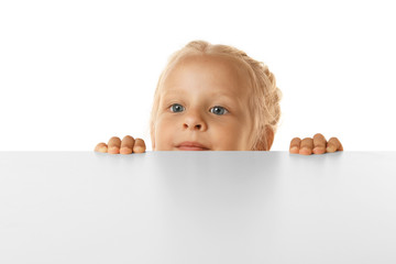 Funny little girl hiding behind white table