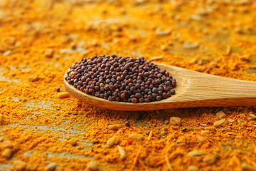 Black mustard seeds in wooden spoon on mixed spices background