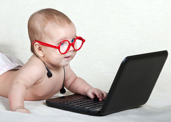Funny kid in glasses with headphones looking at computer © linavita
