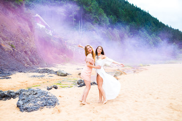 Two girls playing with colorful smoke, happy in nature