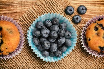 Blueberry muffins and blueberries on sackcloth.