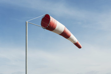 Red and white windsock wind filled blue sky background