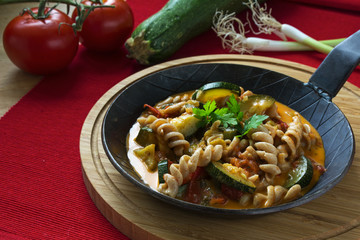 wholemeal pasta with zucchini tomatoe vegetables in a black pan