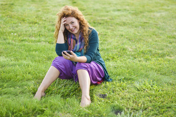 Fototapeta premium woman talking on phone top of the grass