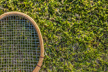 Vintage wood tennis racket on green grass garden