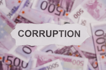 Pieces of torn white paper with CORRUPTION word on money blur background