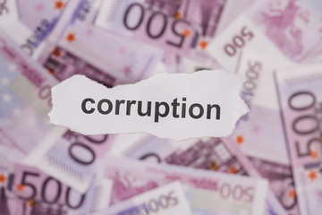 Pieces of torn white paper with CORRUPTION word on money blur