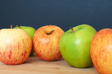 Green and pink apples on a wooden and black background