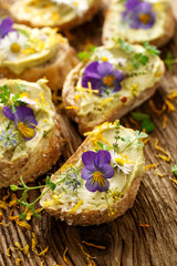 Canapes with eddible flowers and broad bean hummus on a wooden table