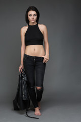 Fashion model wearing leather pants and jacket posing on grey background