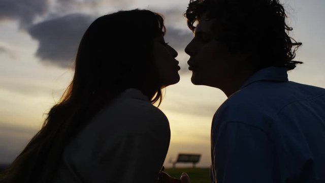 4K Silhouette couple sharing a kiss whilst singing and enjoying the sunset