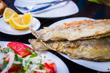fried fish with fresh herbs and lemon