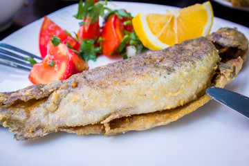 fried fish with fresh herbs and lemon