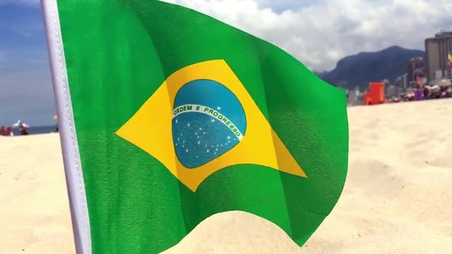 Brazilian flag flying in slow motion in the sand at Ipanema Beach in Rio de Janeiro, Brazil