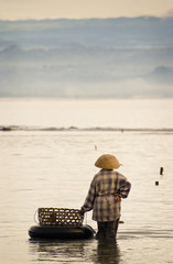 Seaweed Farmer.  On a small island off of the coast of Bali, Indonesia, called Nusa Lembongan, a seaweed farmer takes a break to enjoy the view of the mainland.  © LoweStock