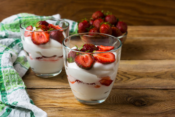 Layered strawberries dessert with cream cheese on rustic wooden