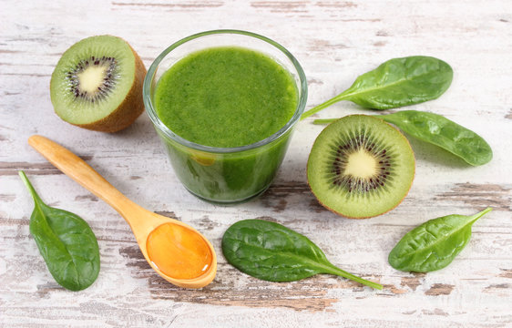 Cocktail from spinach and kiwi with honey on old wooden background, healthy nutrition