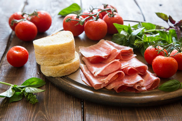 Fototapeta na wymiar Antipasto with ham and bresaola. tomato and basil. 