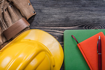 Leather building belt note-books pen hard hat on wooden board co